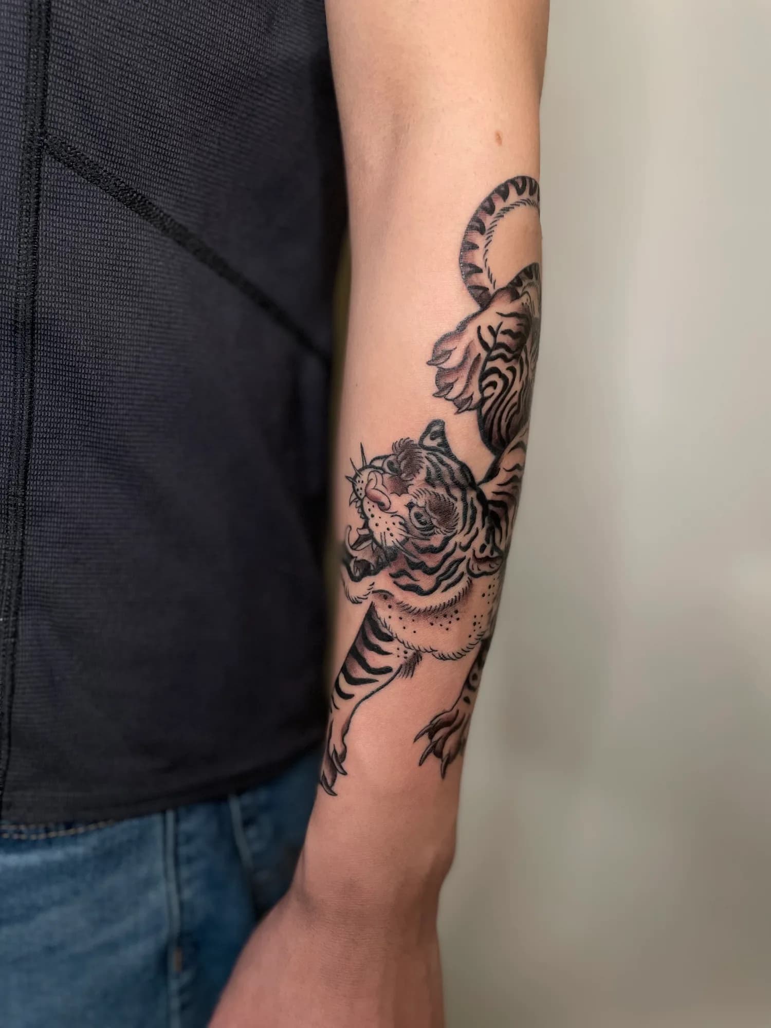 Black and grey climbing tiger forearm tattoo by Kamy Cao.