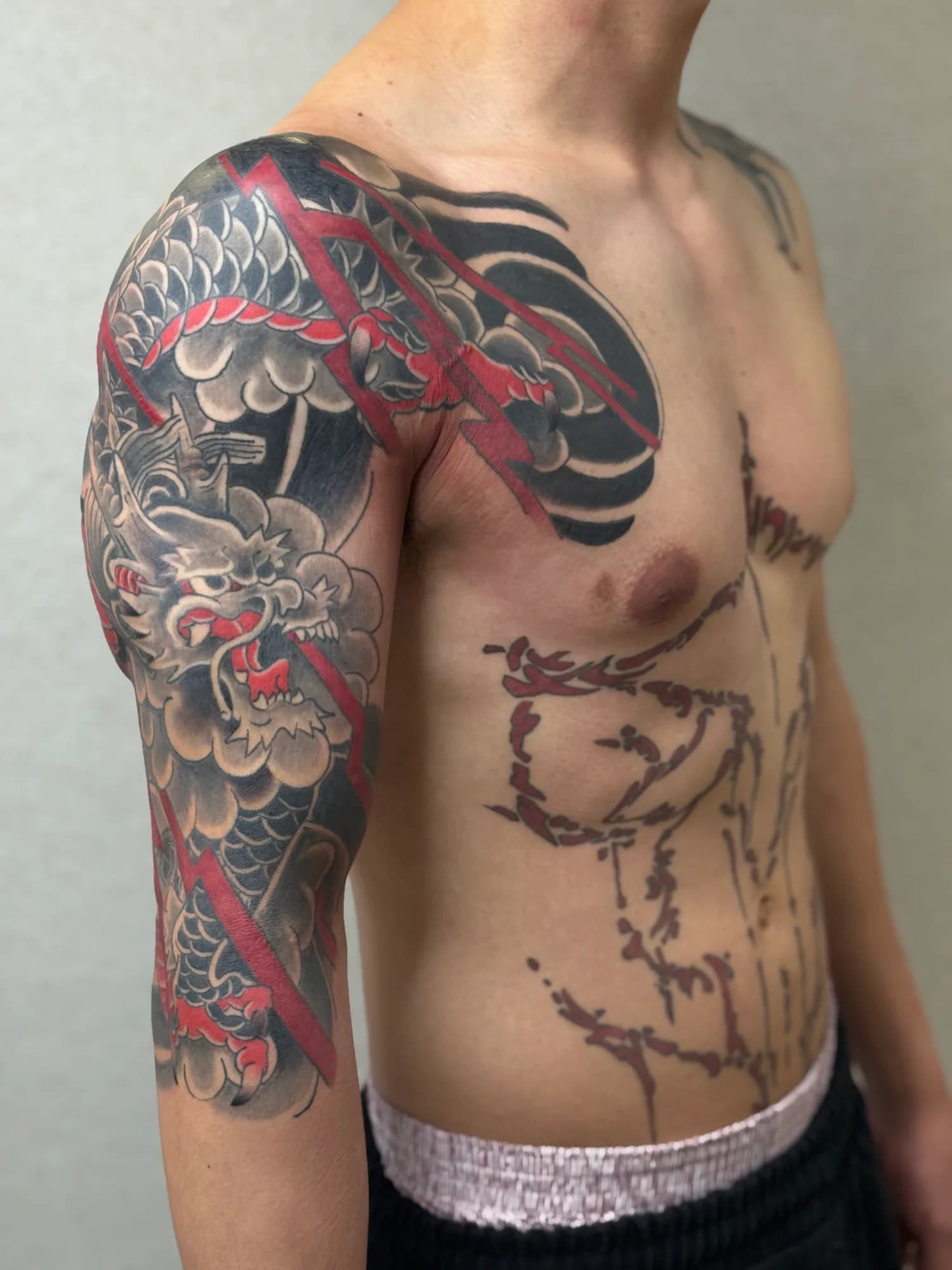 New school Japanese dragon half sleeve tattoo in black and grey with red lightning, by Kamy Cao.