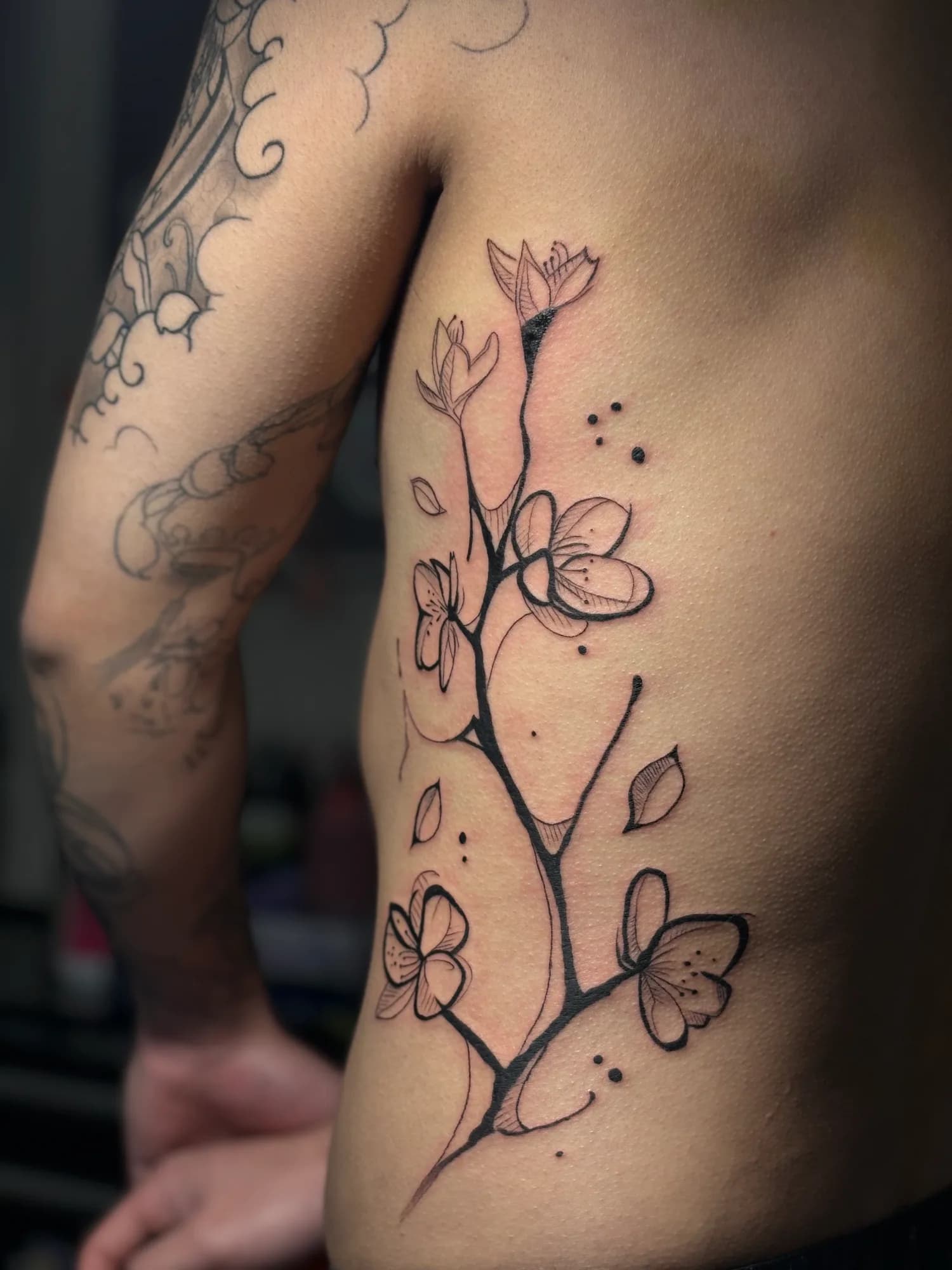 Black and grey abstract sakura branch rib tattoo by Kamy Cao.