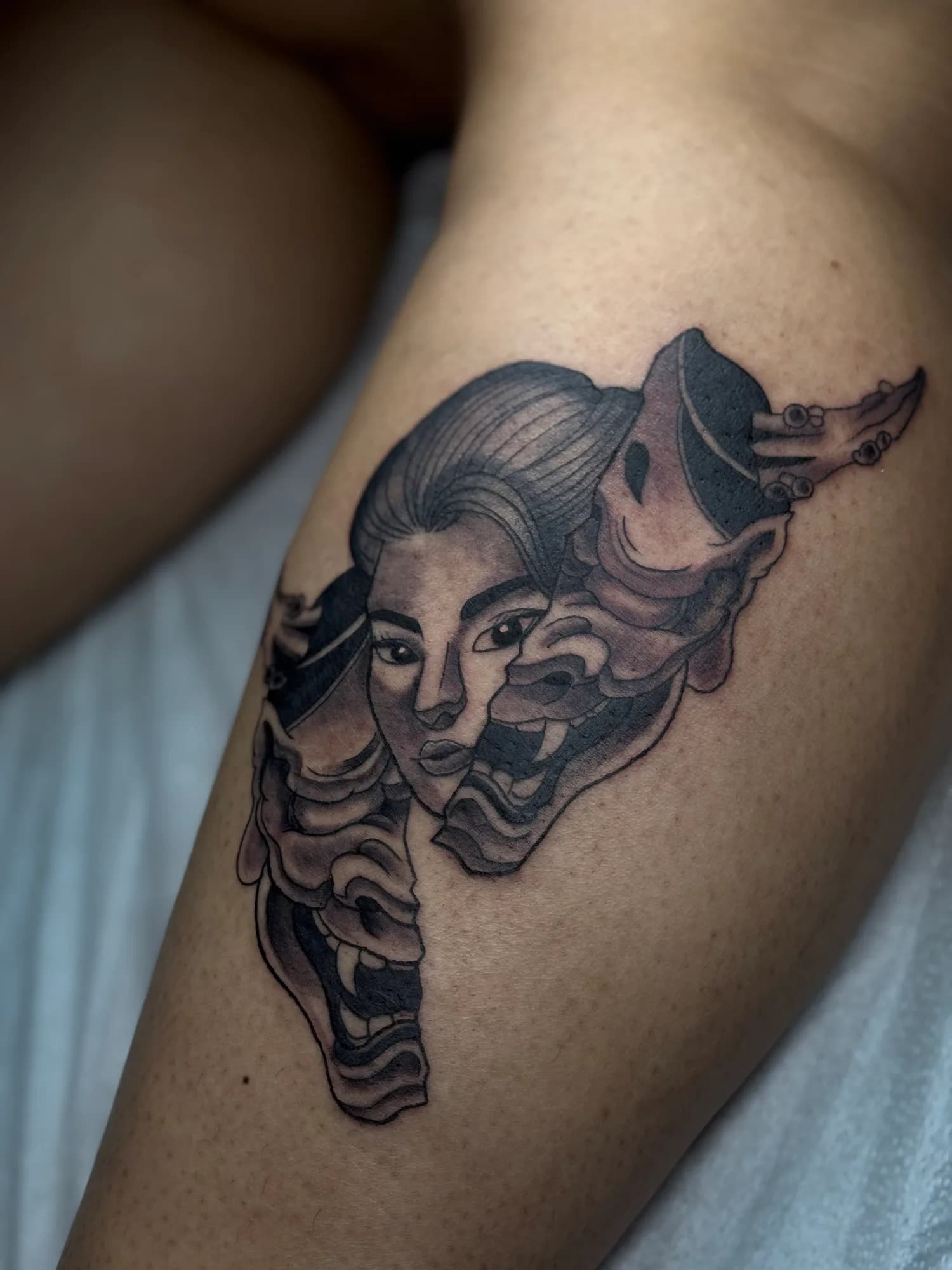 Black and grey Hannya and geisha calf tattoo by Kamy Cao.