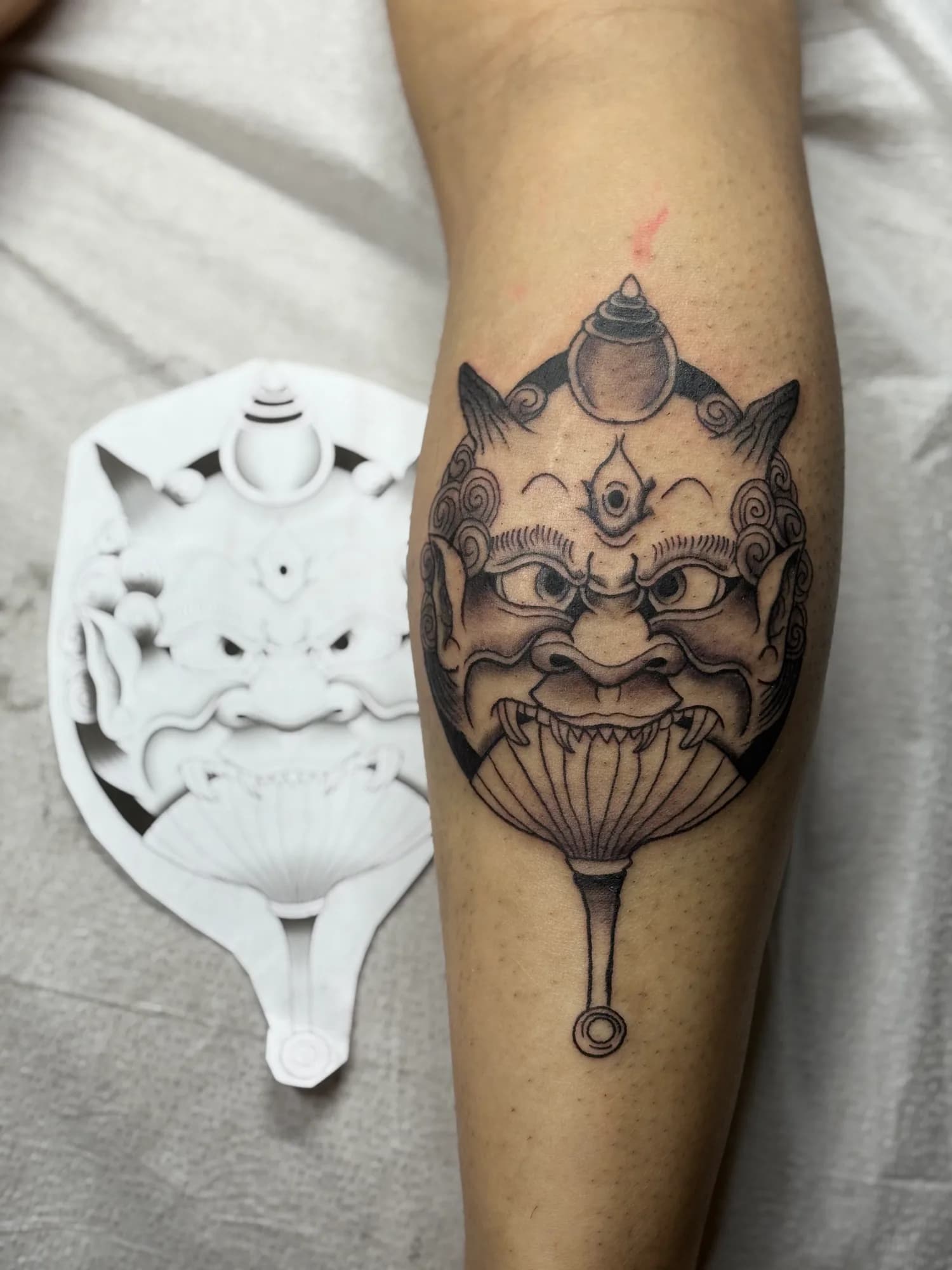 Black and grey Japanese Oni fan calf tattoo by Kamy Cao.